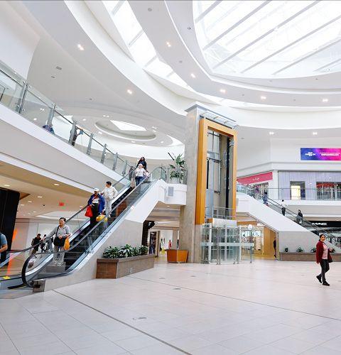 Spacious mall walkway with accessible paths and shoppers moving through popular retail areas
