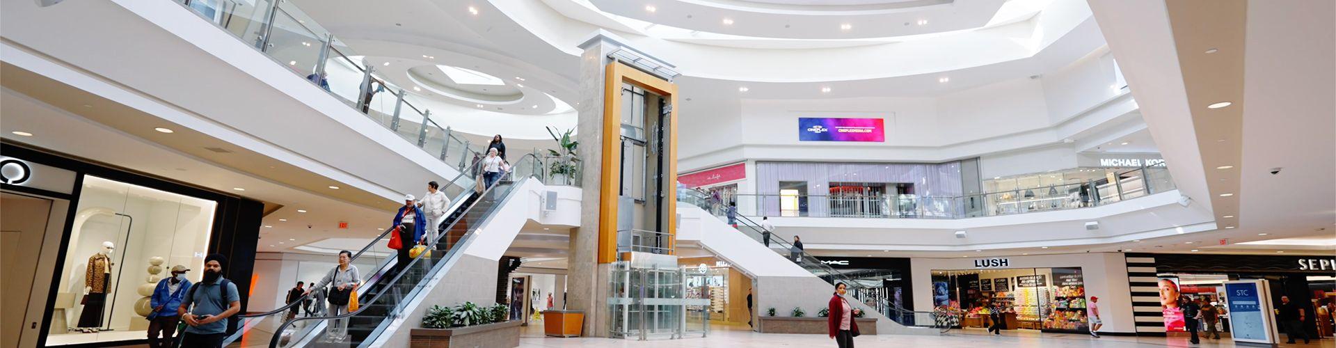 Spacious mall walkway with accessible paths and shoppers moving through popular retail areas