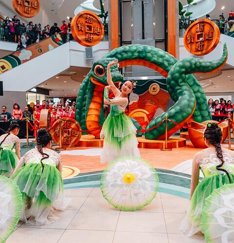 Live cultural dance performance at a mall with performers in green costumes and festive decor