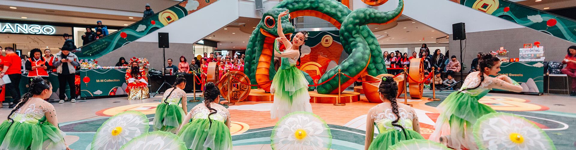 Live cultural dance performance at a mall with performers in green costumes and festive decor