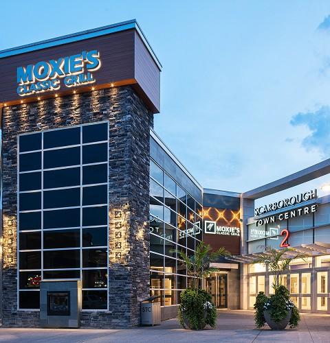 Exterior of Scarborough Town Centre entrance with modern architecture and storefront signage at dusk