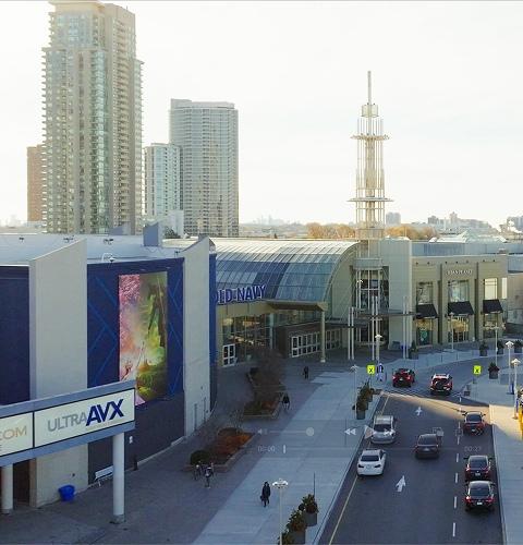 Exterior view of the shopping centre featuring parking areas, storefronts, and main entrance access