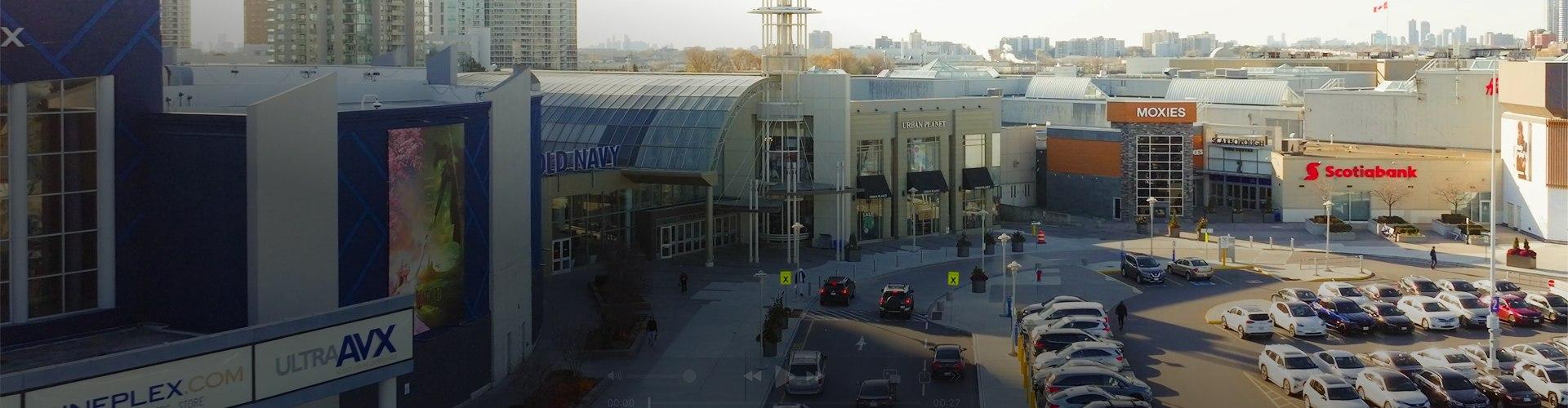 Exterior view of the shopping centre featuring parking areas, storefronts, and main entrance access