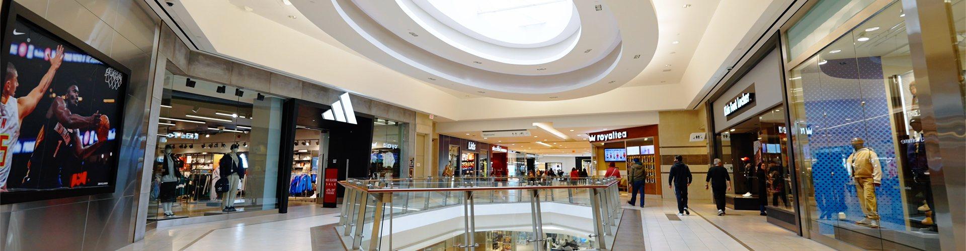 Shopping corridor featuring adidas store with shoppers actively browsing multiple retail outlets