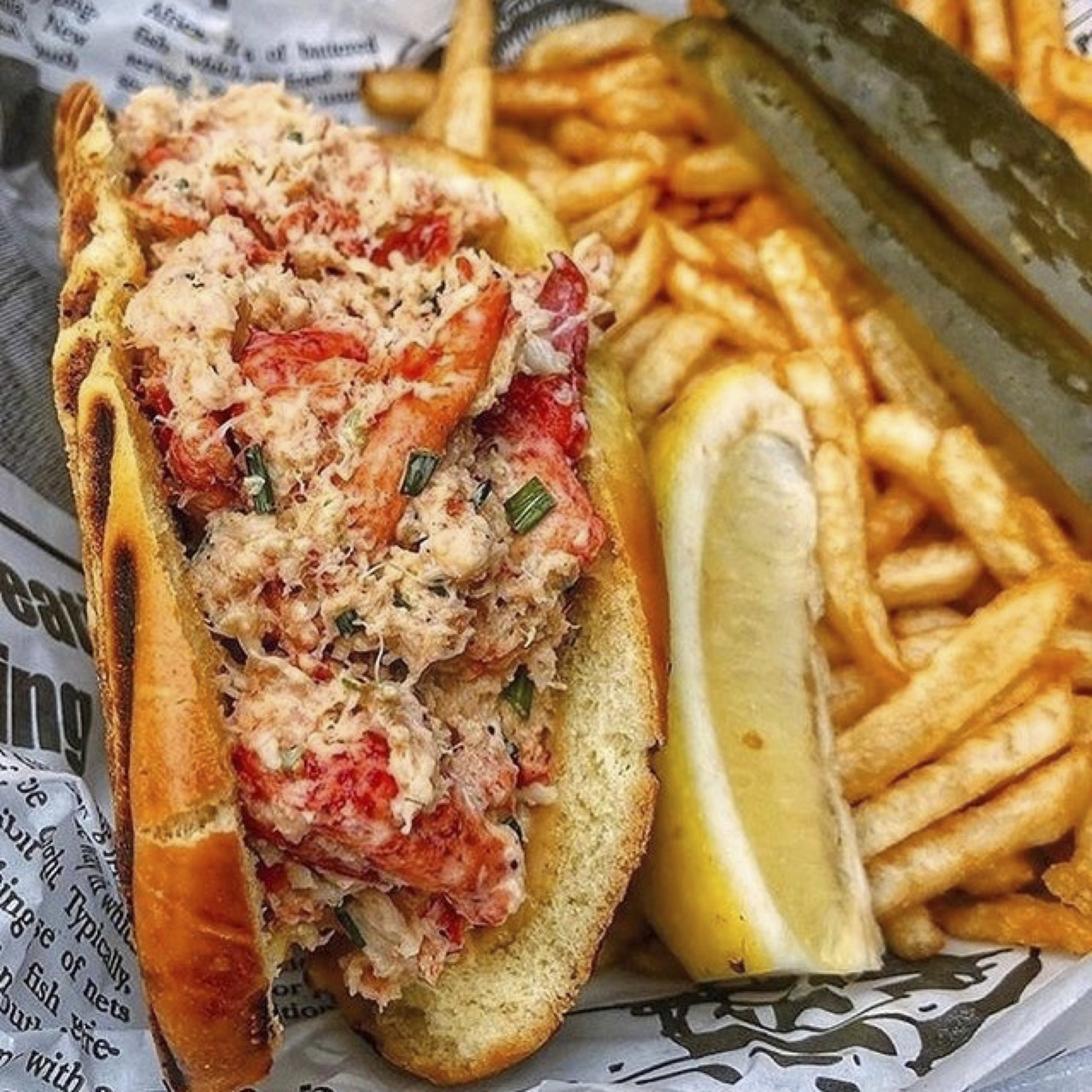 Lobster roll with fries and lemon wedge