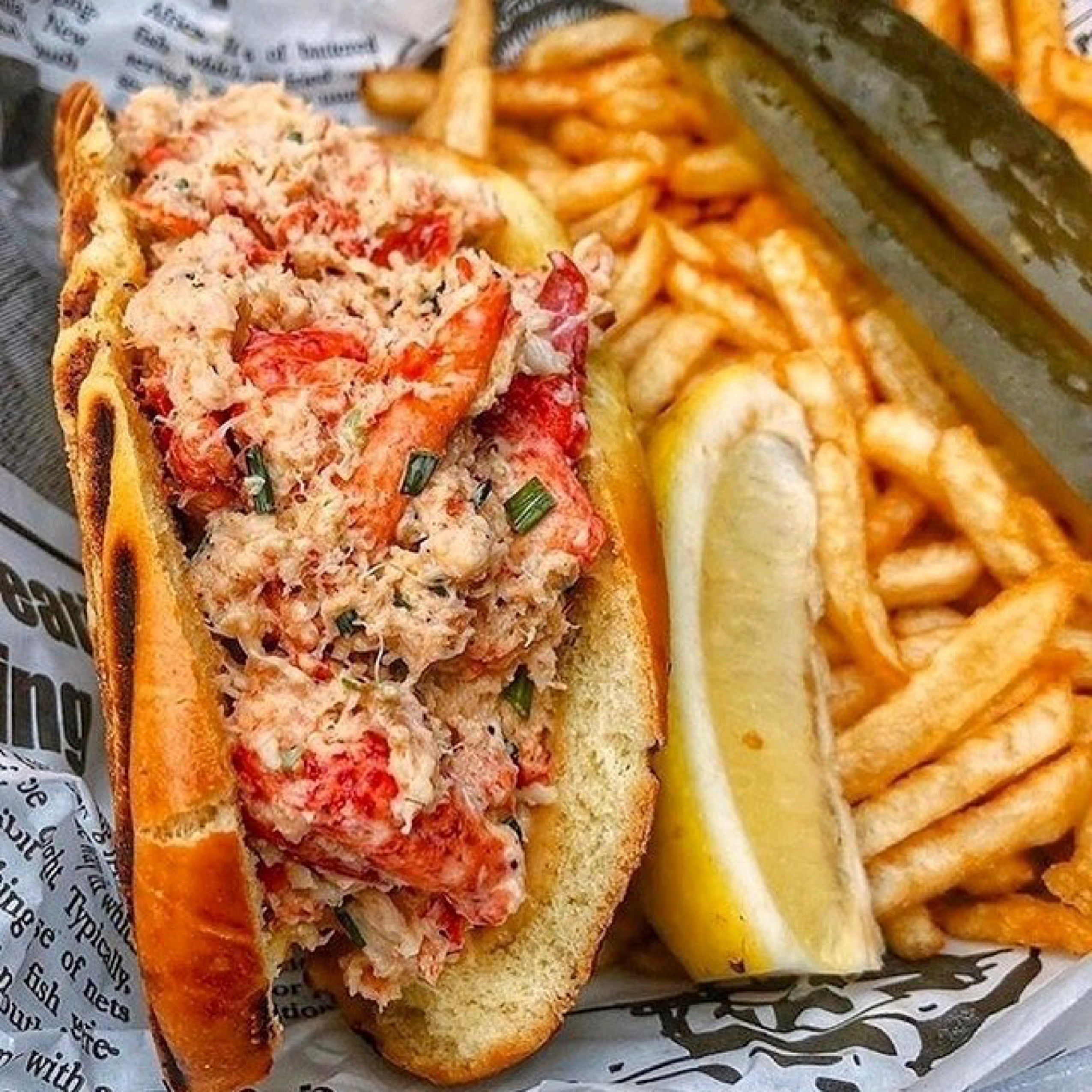 Lobster roll with fries and lemon wedge