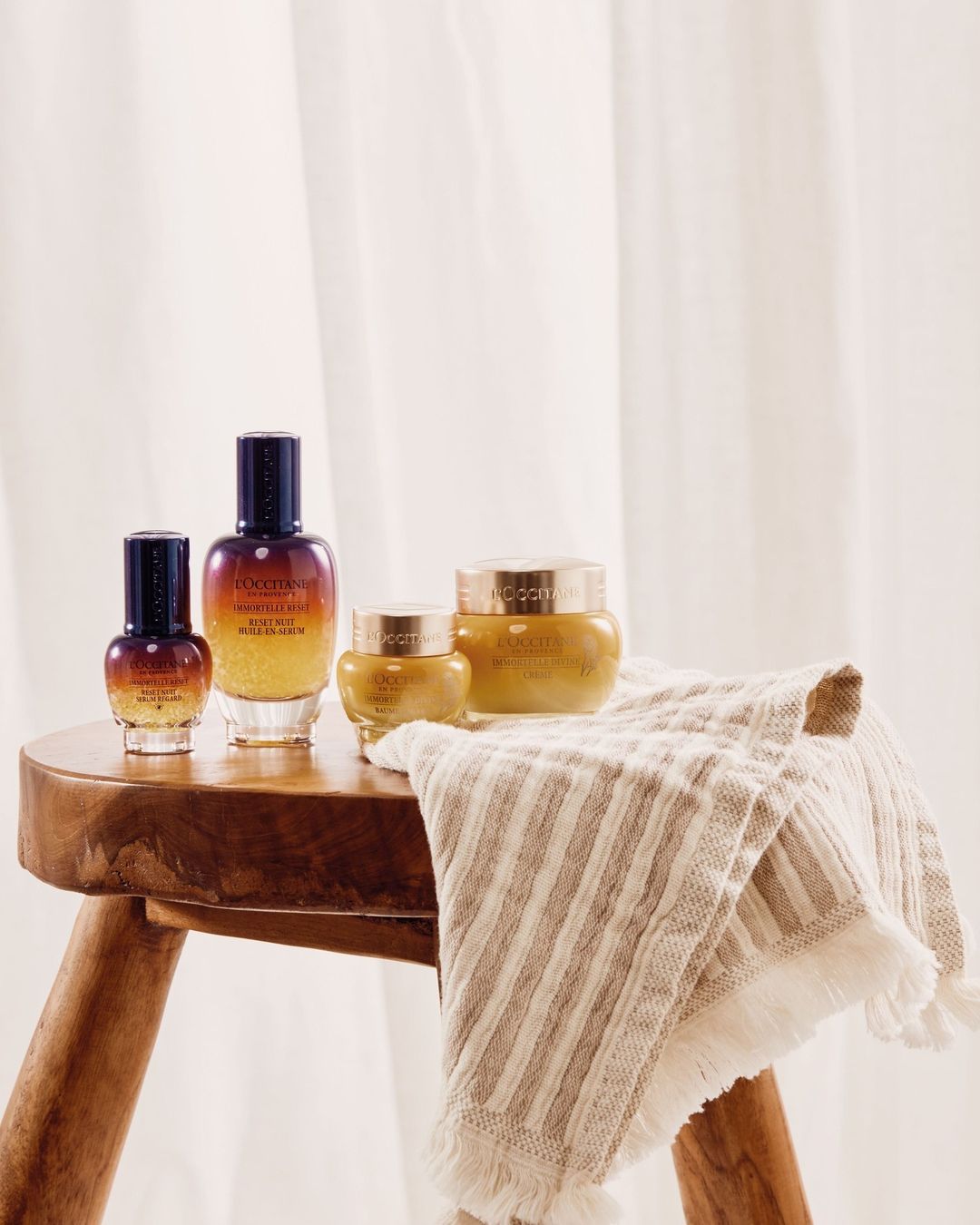 Four skincare products sitting on a wooden tool with a cloth.