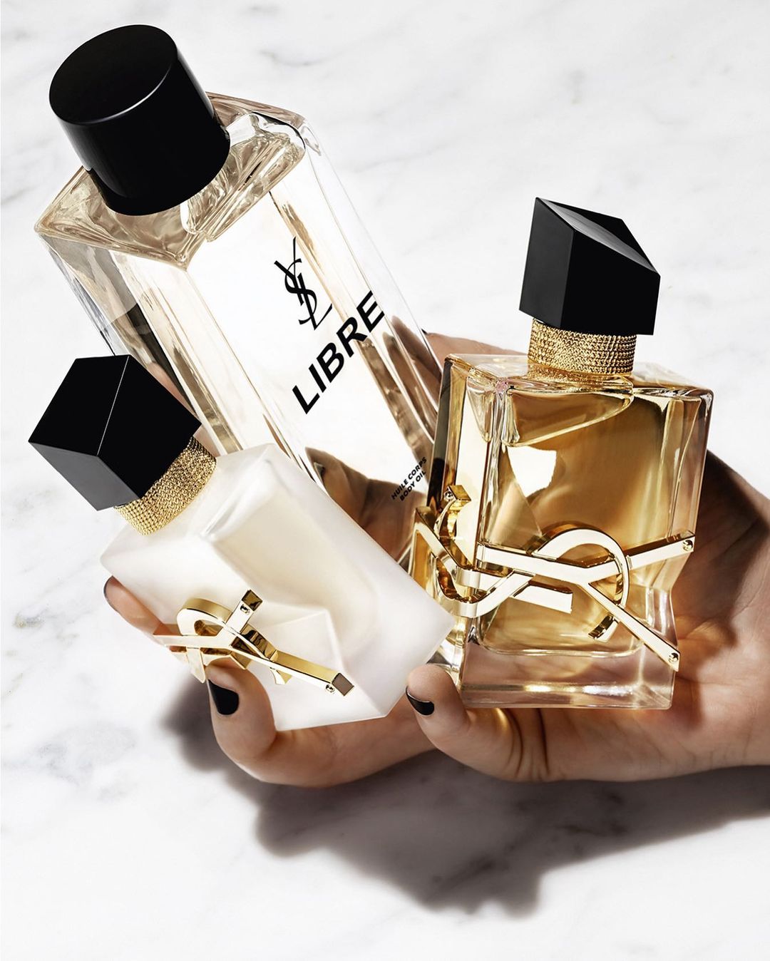 Three golden perfume bottles in someones hand.
