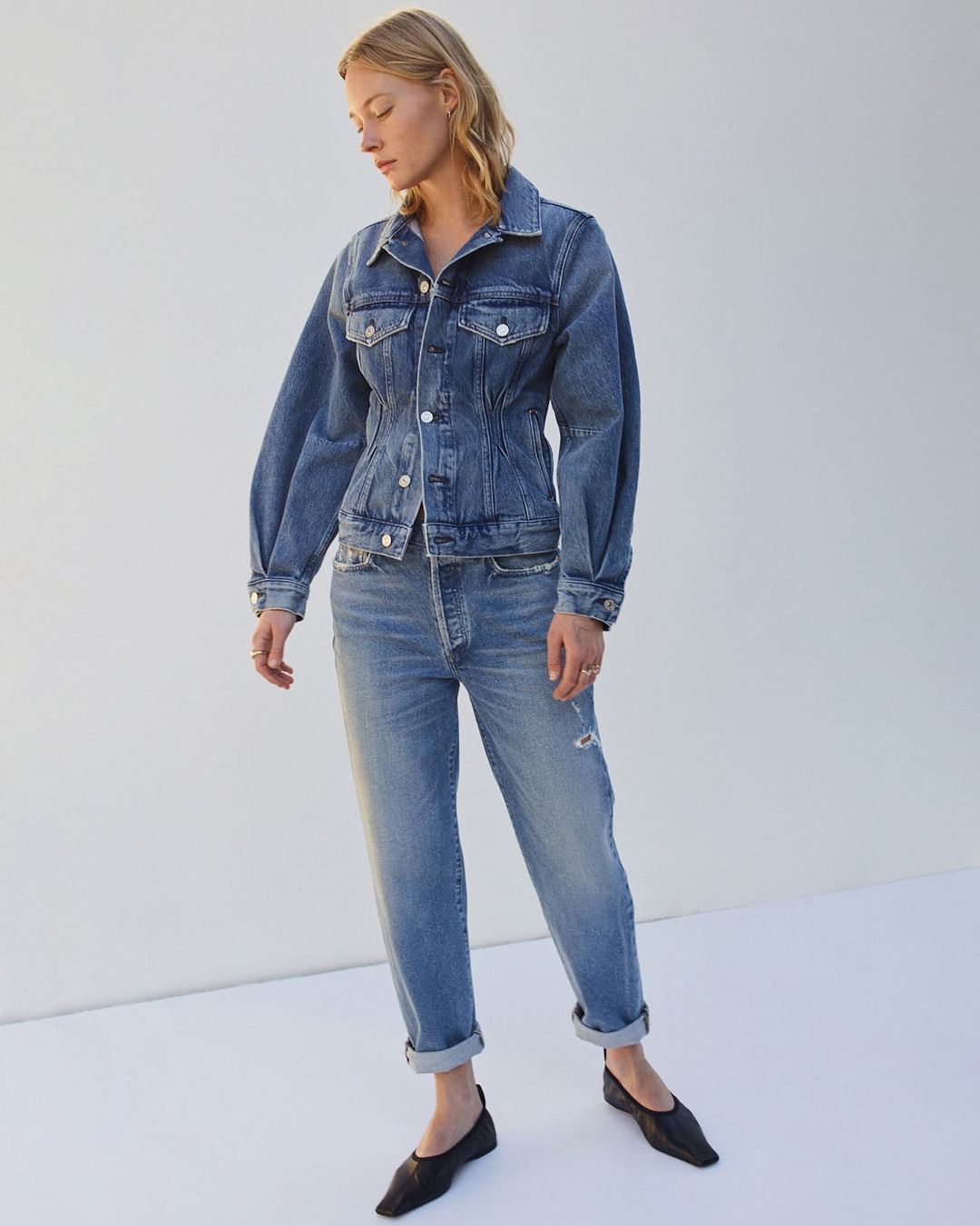 Model wearing black flats, straight-legged denim jeans, and a button-downed denim jacket.