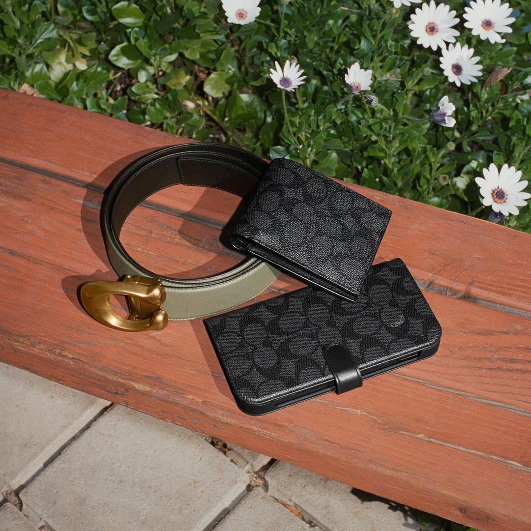 image of coach accessories on a bench: a belt, and two different sized wallets