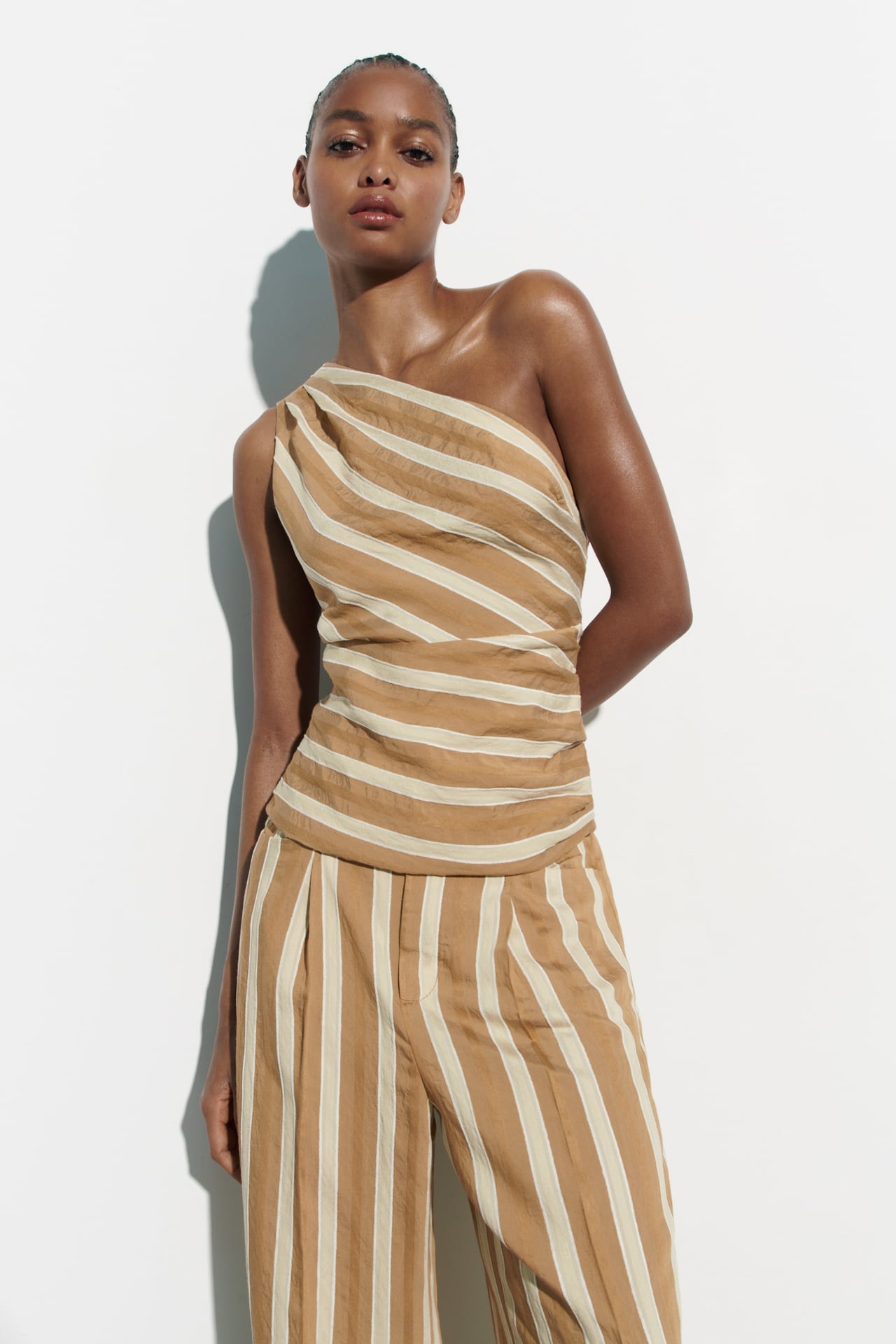 image of a model wearing a matching yellow and cream striped set from zara. The top is one shouldered and the pants are baggy