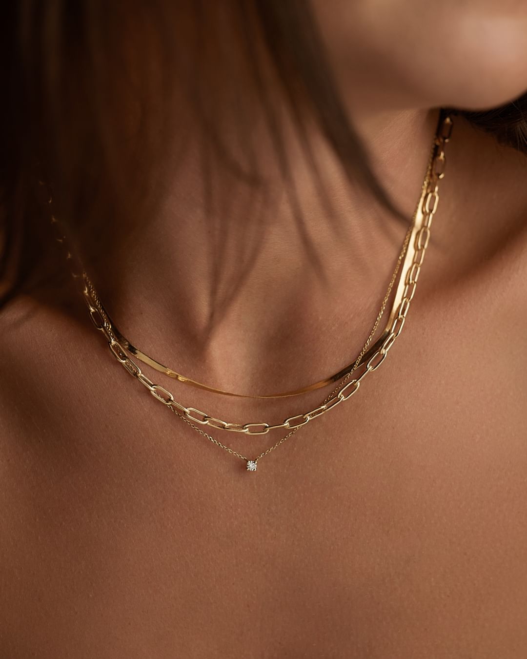 close-up image of model wearing layered gold necklaces