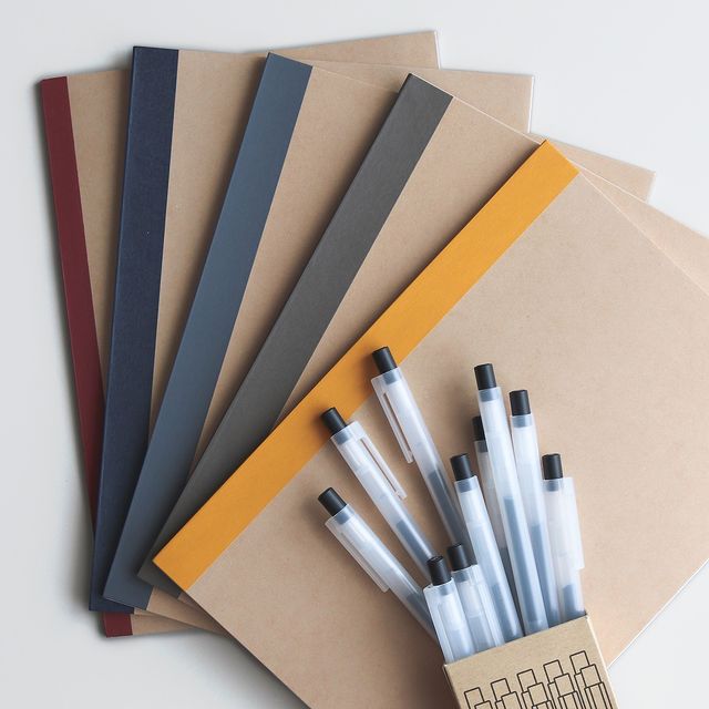 flat lay image of various notebooks fanned out with a pens spilling out of a box over top