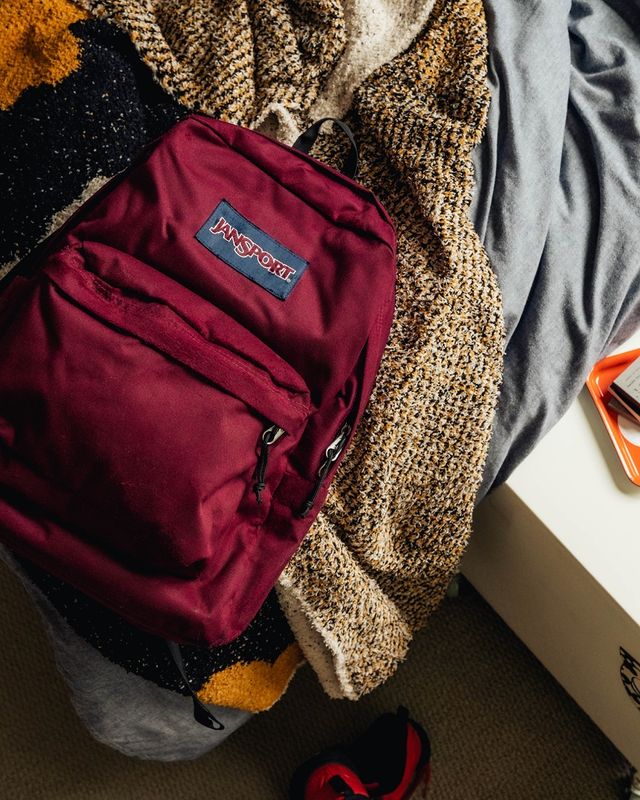 burgundy jansport backpack on a bed