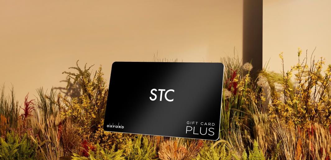 promotional image of a black STC gift card atop fall foilage