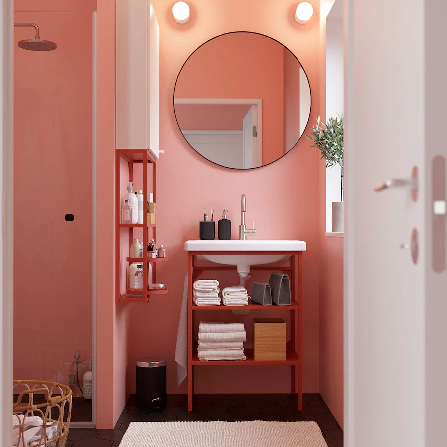 image of a pink bathroom. in the frame is the sink and a round mirror