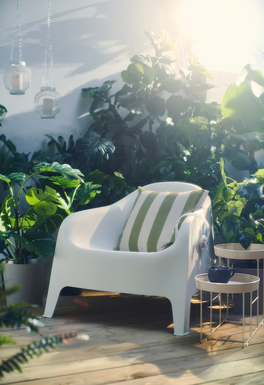 white ikea armchair outdoors surrounded by greenery and sunlight