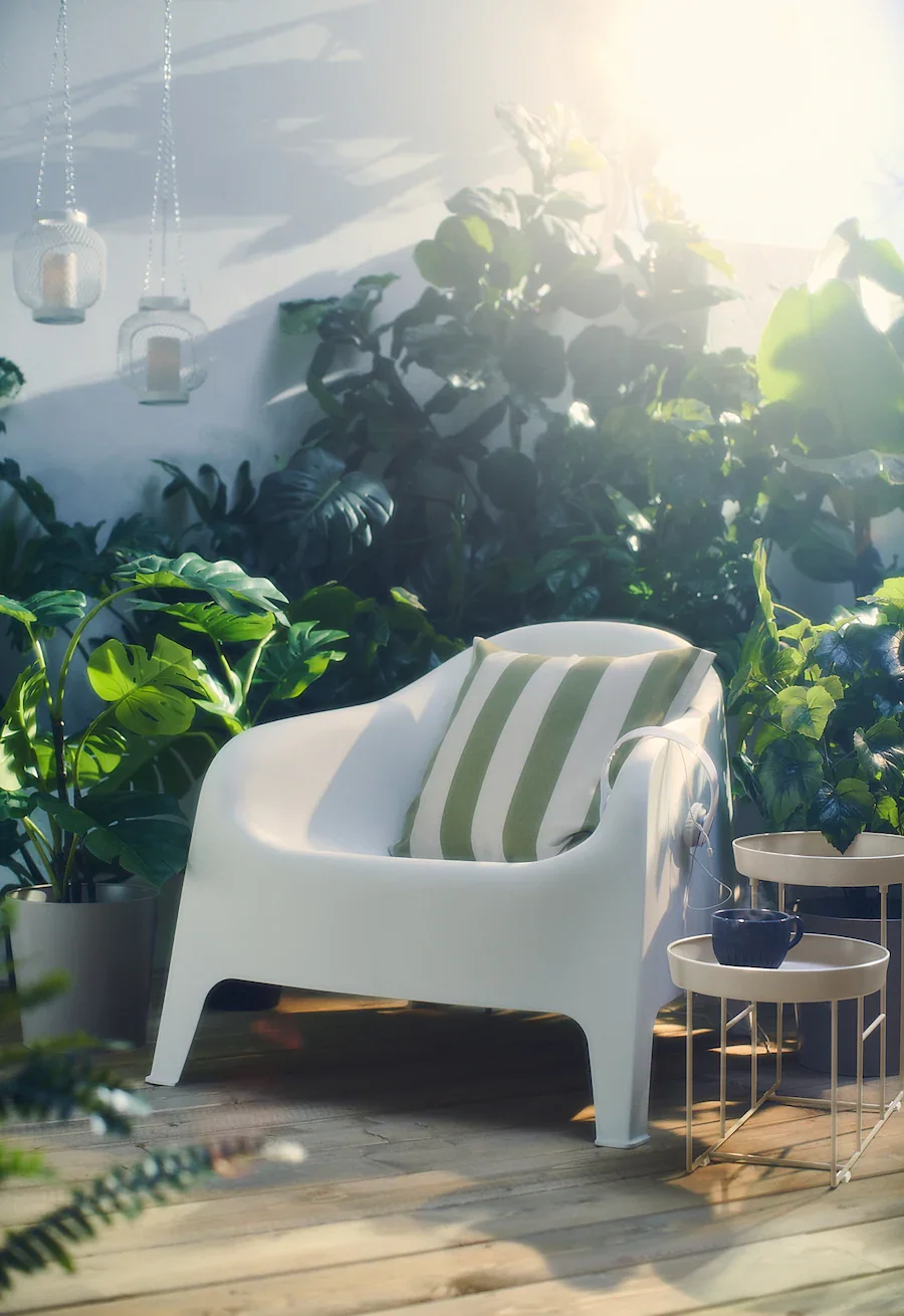 white ikea armchair outdoors surrounded by greenery and sunlight