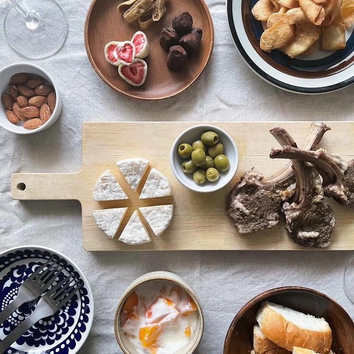 a table with plates of food, a charcuterie board, and glasses