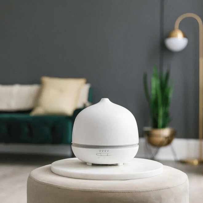 a white essential oil diffuser on a stool in a room
