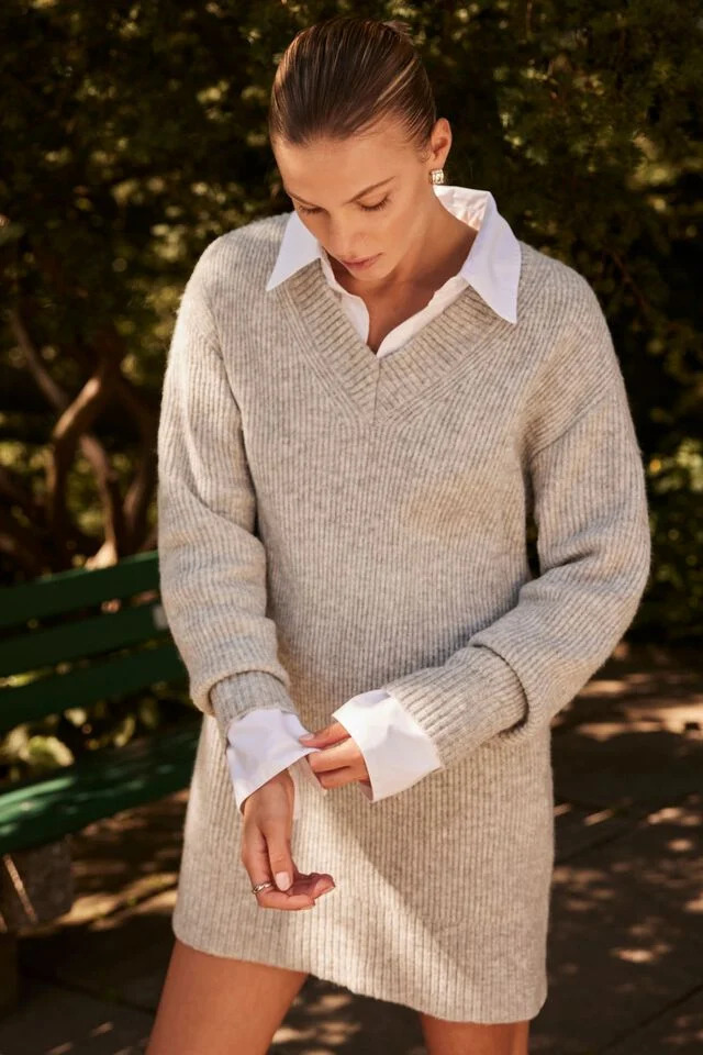 a person in a neutral sweater dress with a white collared shirt