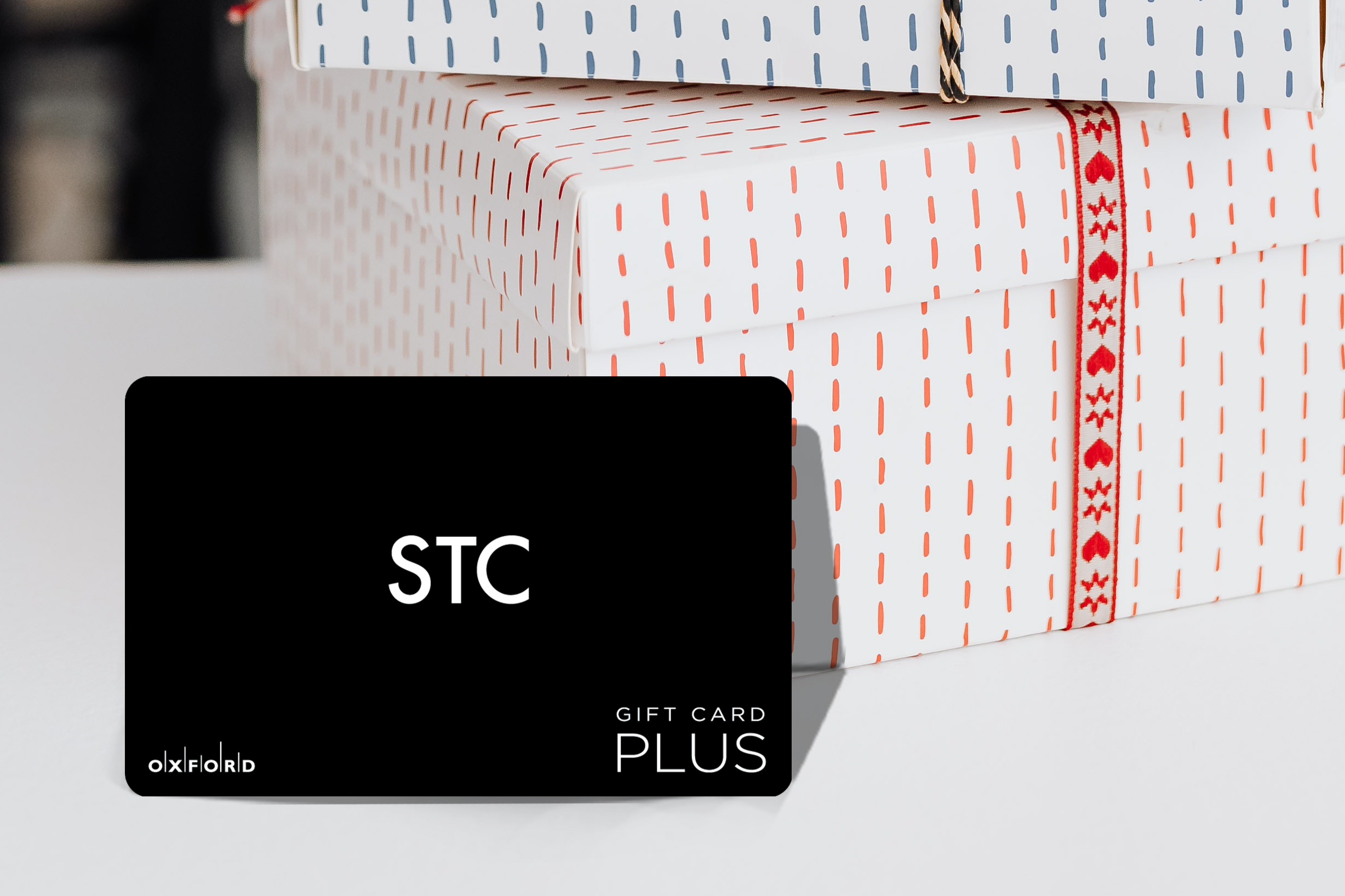 promotional image of a black STC gift card perched in front of two gift boxes