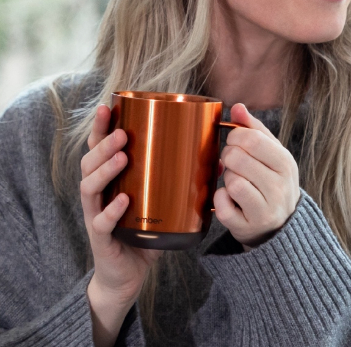 A woman holding a copper mug in her hands.