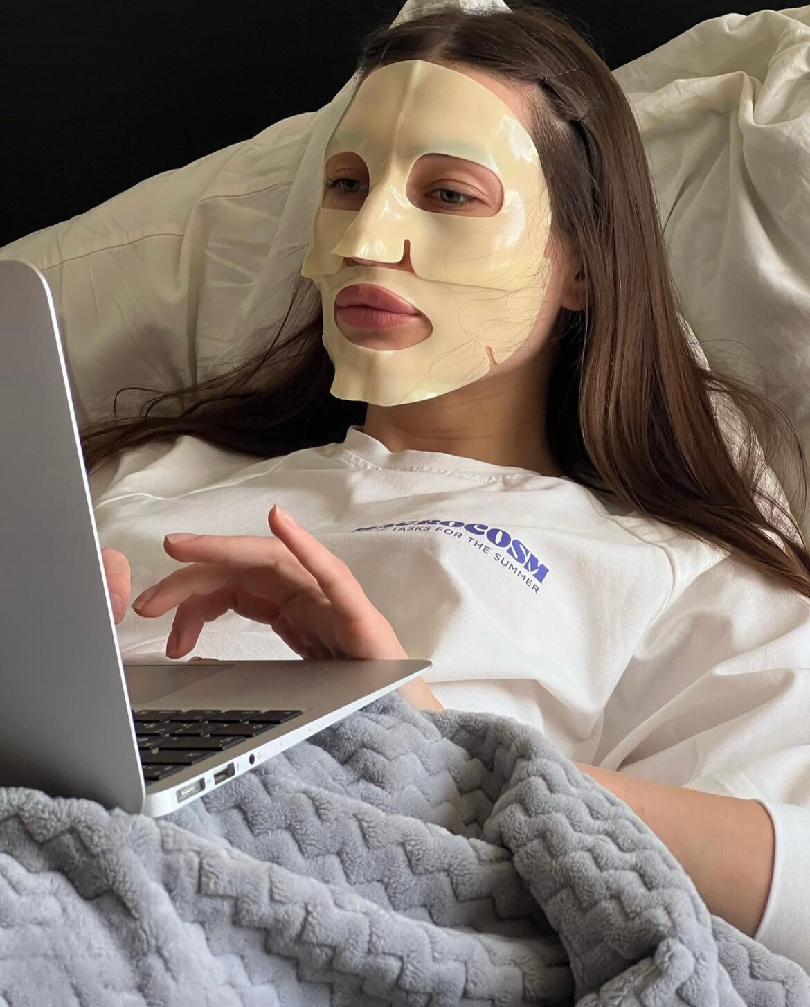 A woman wearing a jelly face mask working on her laptop.