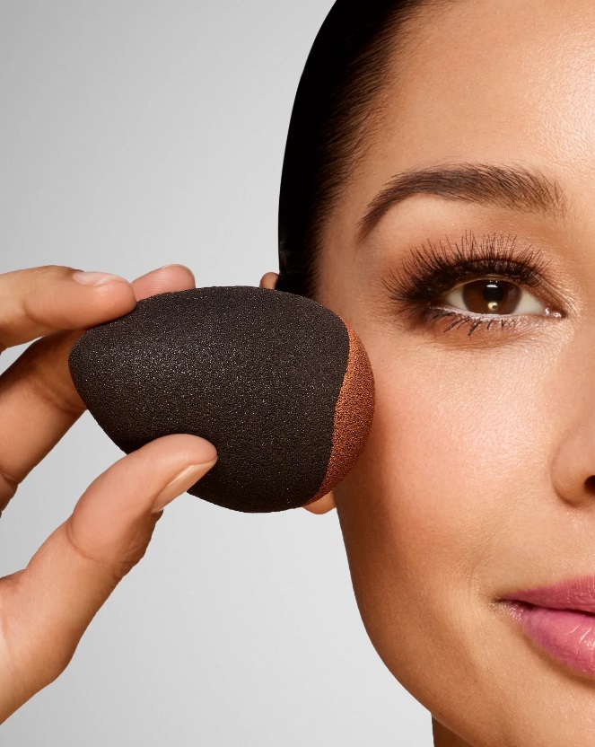 beauty blender being used to apply foundation to a woman's face