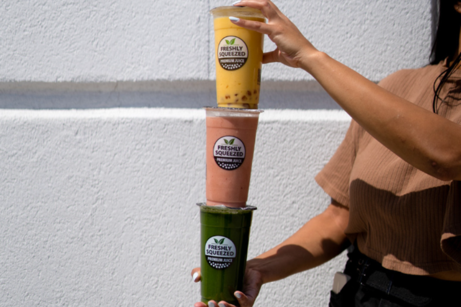 lady holding 3 freshly squeezed drinks