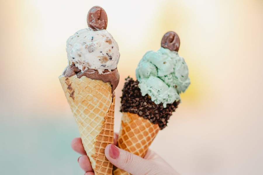 a person holding 2 ice cream cones