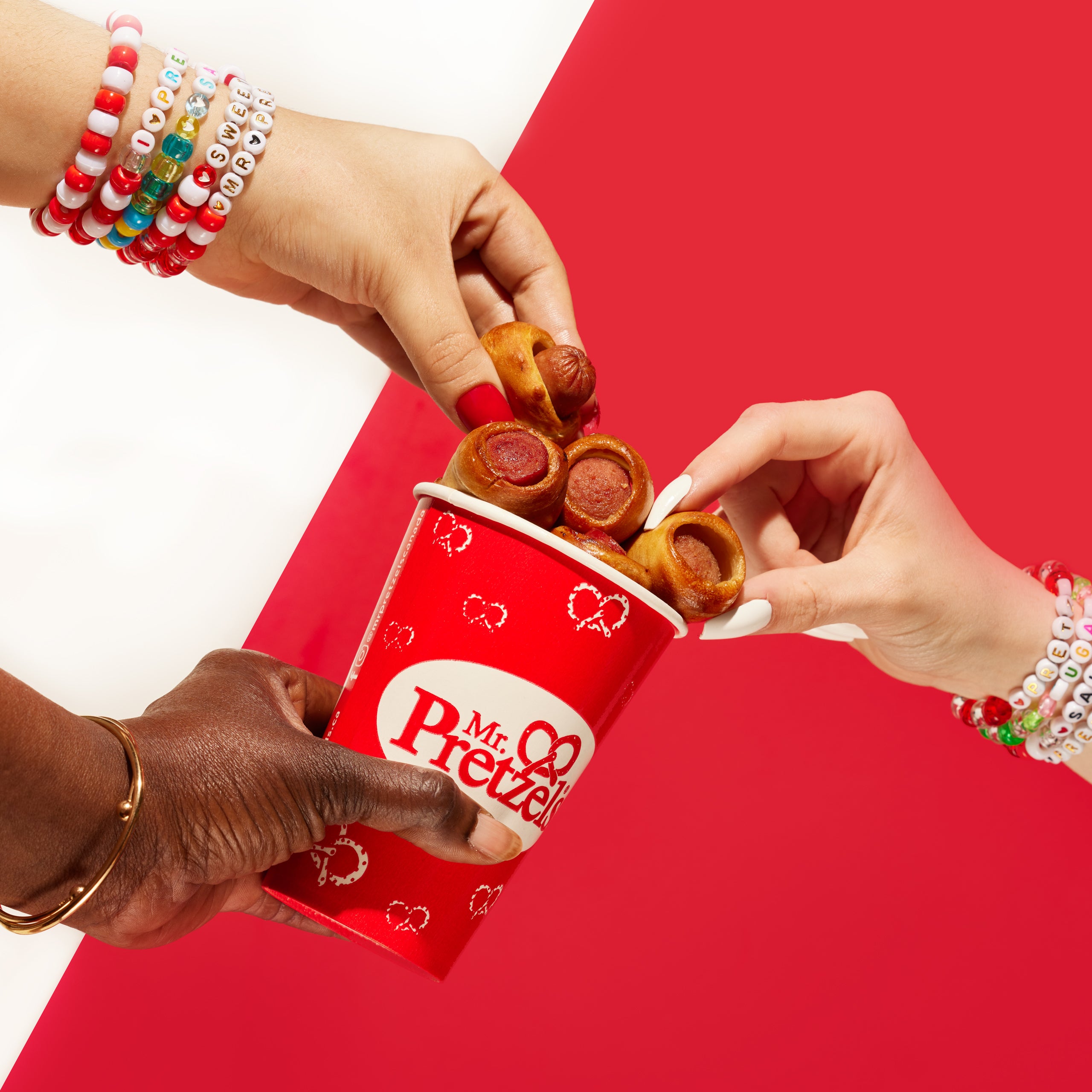 3 people grabbing a sausage pretzel bite from a cup