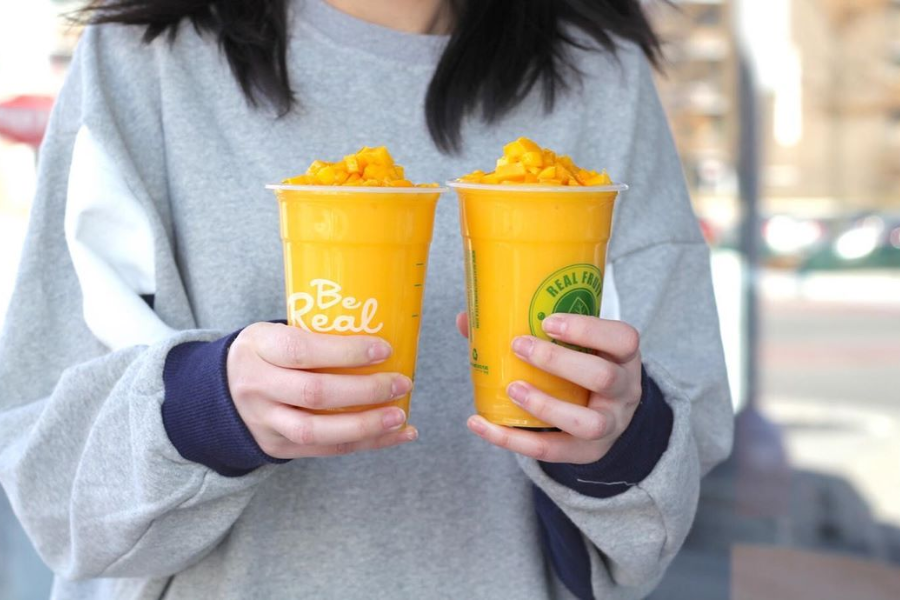 a person holding two diamond mango slush