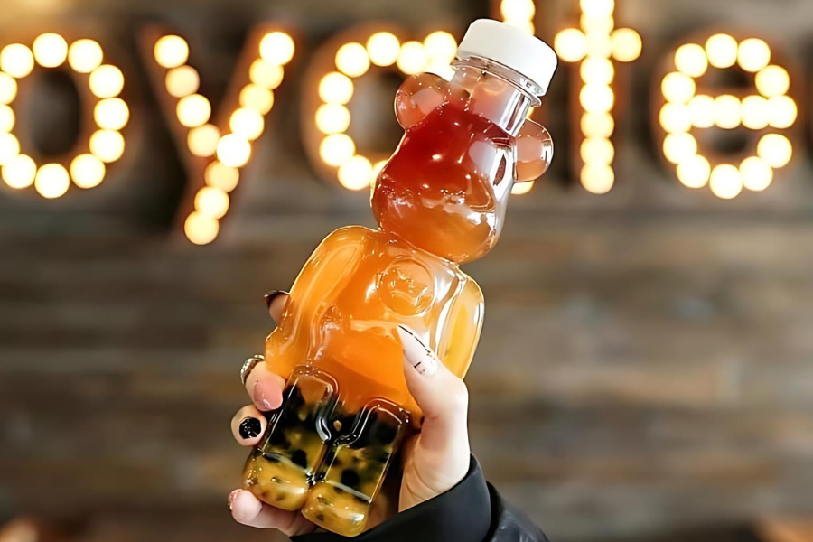 a person holding a bear bottle bubble tea in air