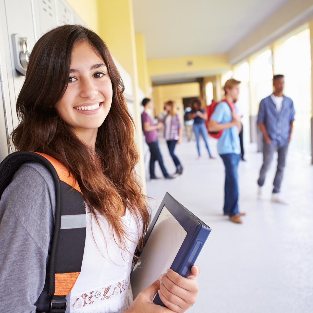 a girl holding binders by lockers