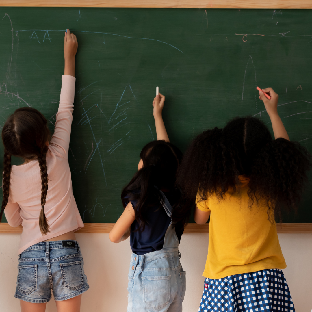 3 kids writing on a chalkboard