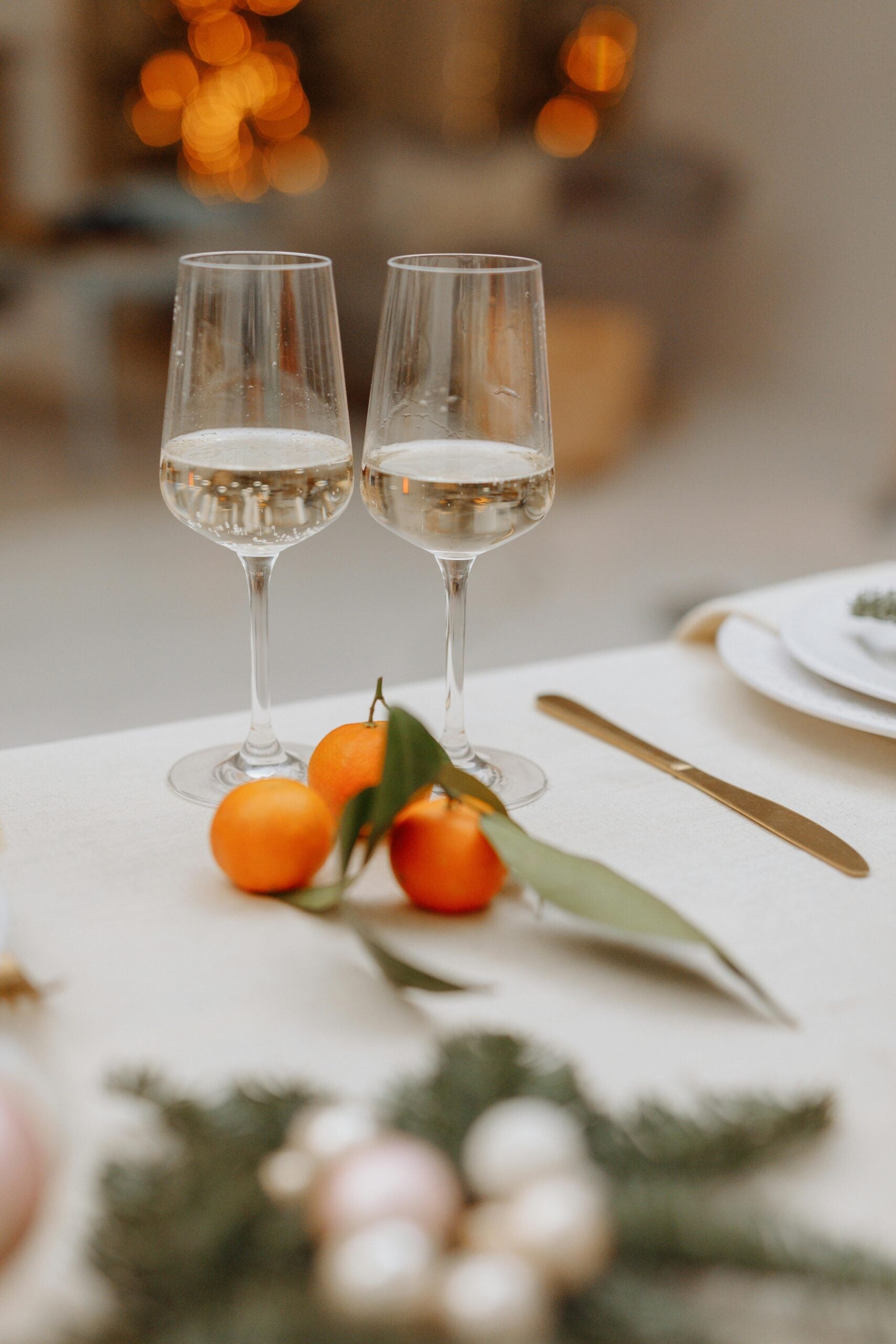 Two champagne glasses on a set table with fruits.