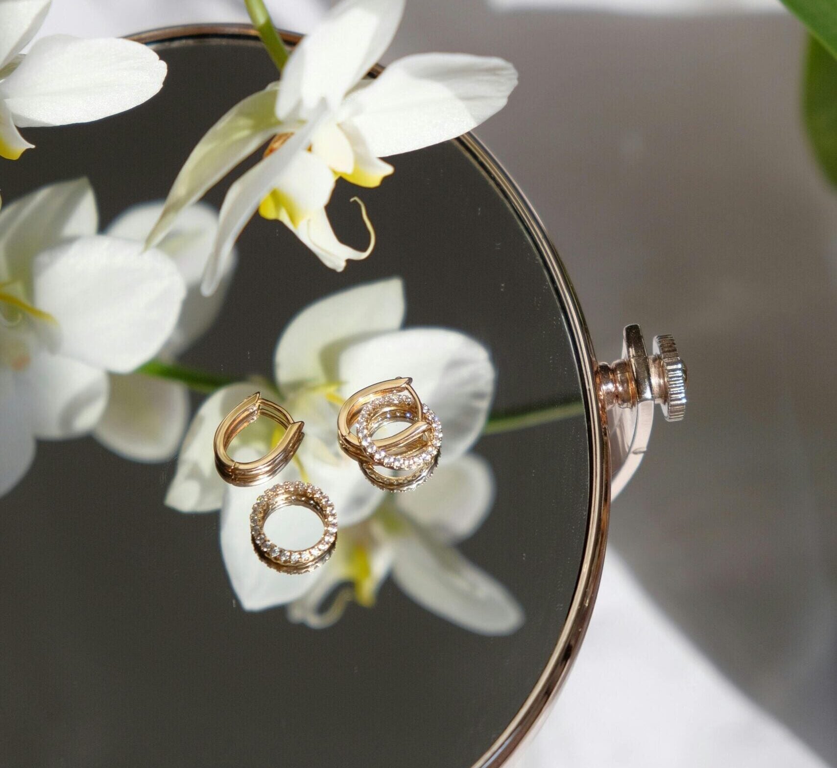 Jewellery sitting on a table with an orchid flower.