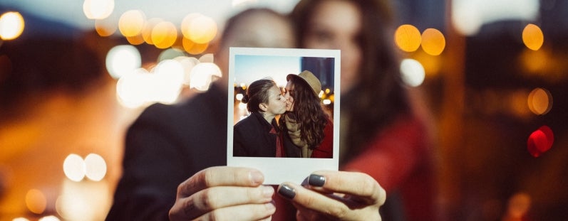 a couple holding up a polaroid picture of themselves