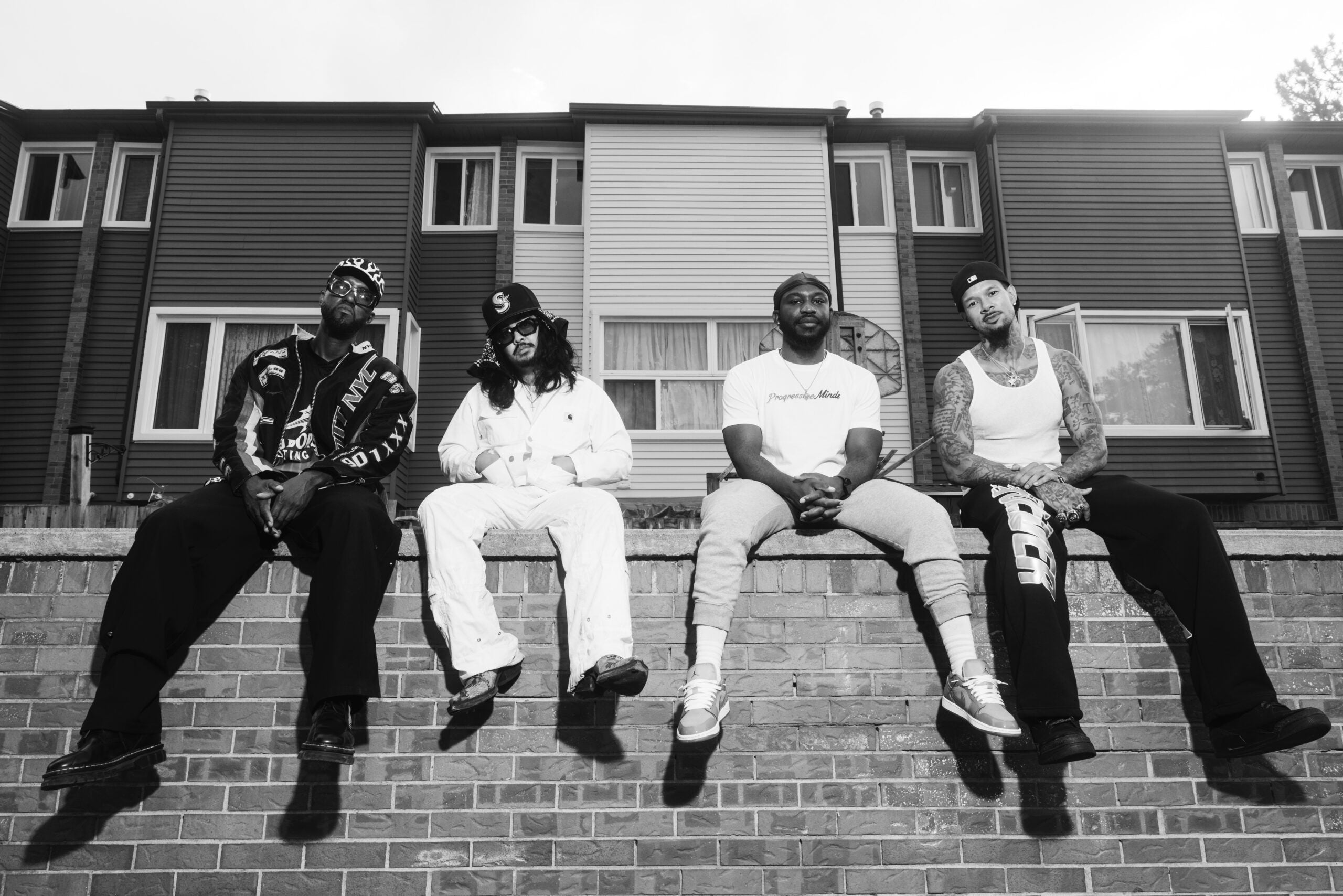 4 men sitting on a railing